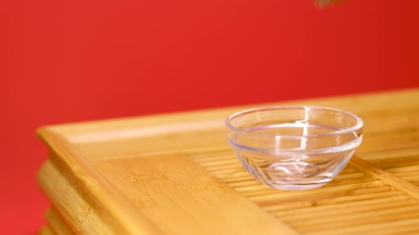 把中国茶倒进一只玻璃碗里,放在木制托盘上. — 图库视频影像