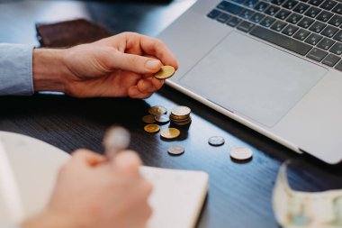 Bir iş adamı para sayar ve bir defter yazar..