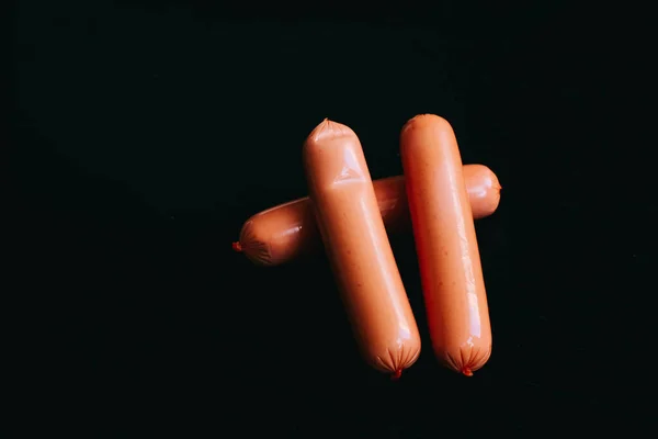 Sausages on a black background. three nipples. — Stock Photo, Image
