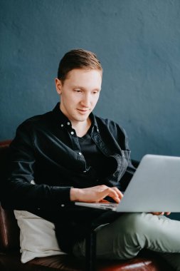 Evde dizüstü bilgisayar kullanan yakışıklı bir genç..