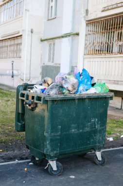 Prefabrik bir evin arka planında tam çöp kutusu