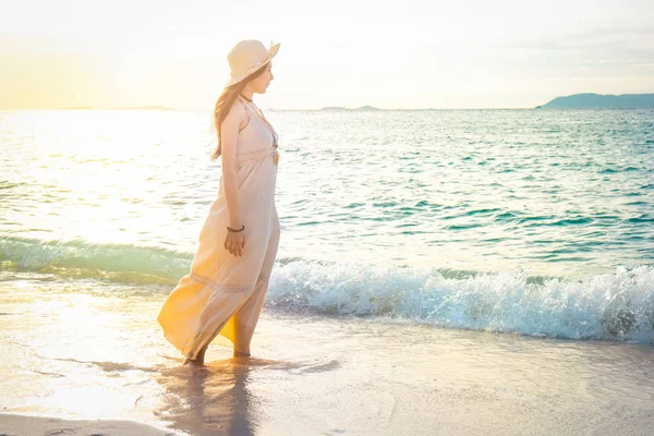 Frau in cremefarbenem Kleid spaziert am schönen Strand bei Sonnen — Stockfoto