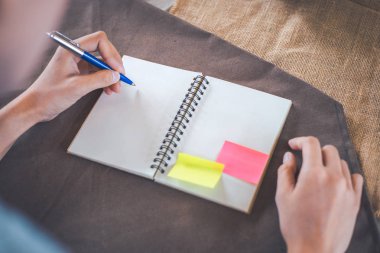 Kadın el üzerinde boş bir not defteri bir kahverengi bir kalemle yazma 