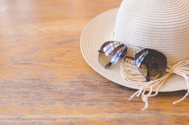 Hasır şapka ile güneş gözlüğü ahşap arka plan üzerinde.