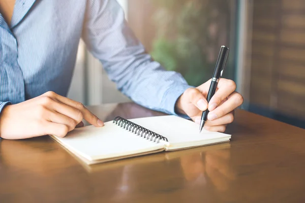 Kvinnlig hand skriver på anteckningsblock med penna i office. — Stockfoto