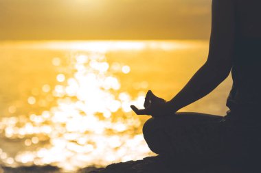 Genç kadın siluet meditasyon ve yoga bea üzerinde uygulamak