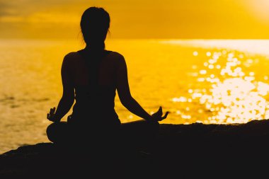 Genç kadın siluet meditasyon ve yoga bea üzerinde uygulamak