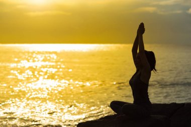 Genç kadın siluet meditasyon ve yoga bea üzerinde uygulamak