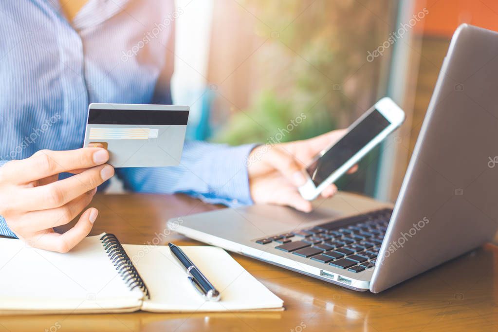 Business woman hand holds a credit card and uses a telephone to 