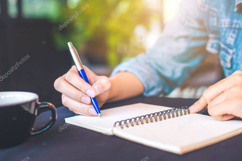 Woman hand is writing on a note pad with a pen in the office.
