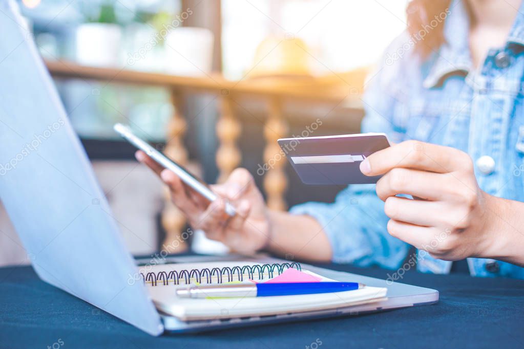 Women hold credit cards and use mobile phones to shopping online