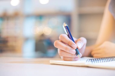 İş kadını eli kalemle not defterine yazıyor..