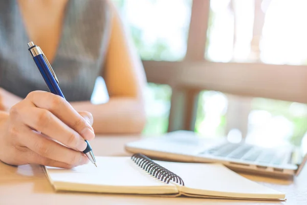 Femme d'affaires main écrit sur le bloc-notes avec stylo dans le bureau . — Photo