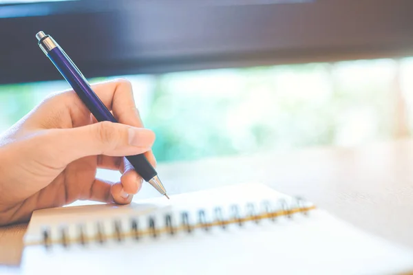 Mujer mano está escribiendo en un bloc de notas con un bolígrafo . — Foto de Stock