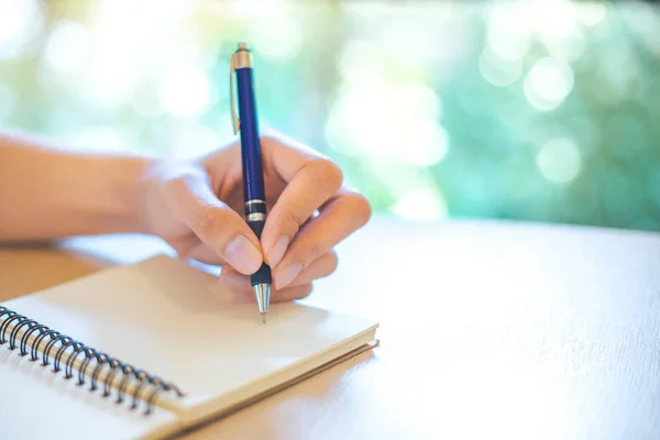Geschäftsfrau schreibt mit einem Stift in der Hand auf einen Notizblock — Stockfoto
