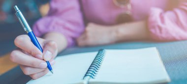 Woman hand taking notes on a notebook using a pen.