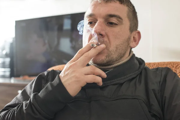 Homem fuma um cigarro em casa . — Fotografia de Stock