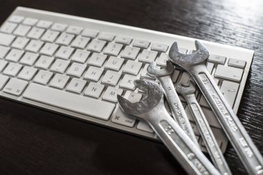 Spanners and white keyboard on background.