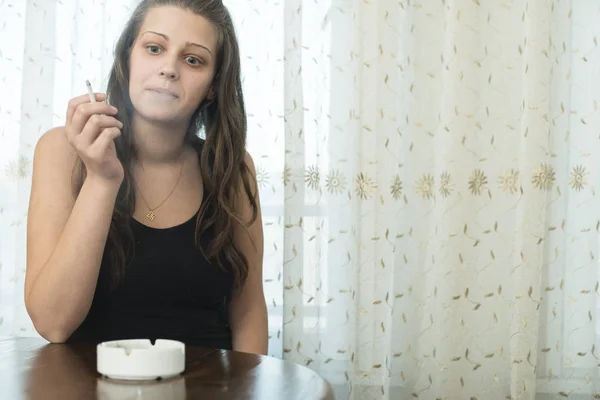Κορίτσι καπνίζει τσιγάρο και κατέχει το τασάκι. — Φωτογραφία Αρχείου