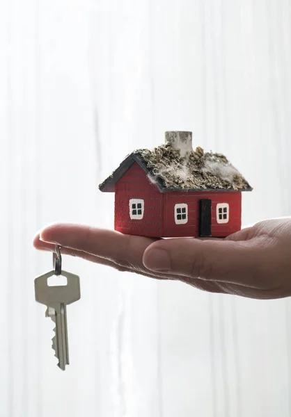 Mão segura casa em miniatura e chave — Fotografia de Stock