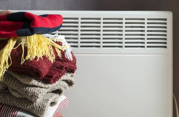 Winter clothes stacked in front of heater.