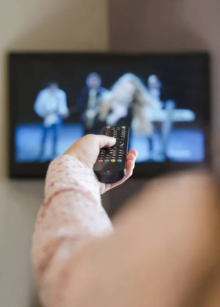 TV, és kezét tartsa távirányító. — Stock Fotó