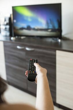 Elini tut Tv uzaktan kumanda. TV arka planda.