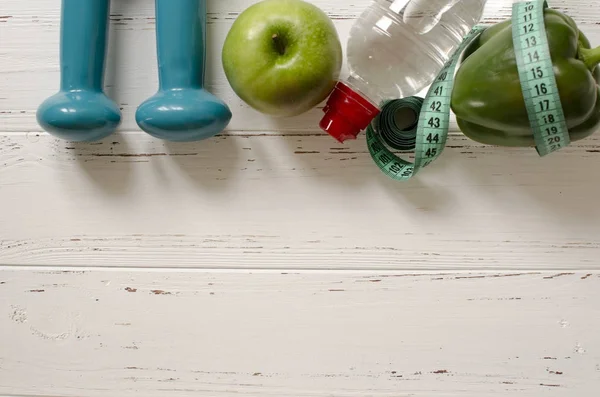 Két súlyzók, üveg víz, zöld alma, centiméter, fehér — Stock Fotó