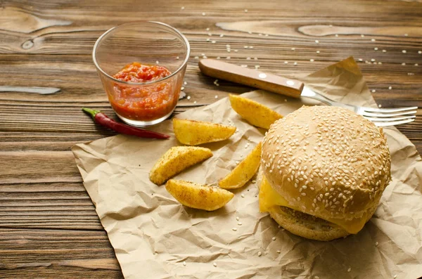 Cheeseburger com batatas fritas e molho de pimenta em um pa artesanato — Fotografia de Stock