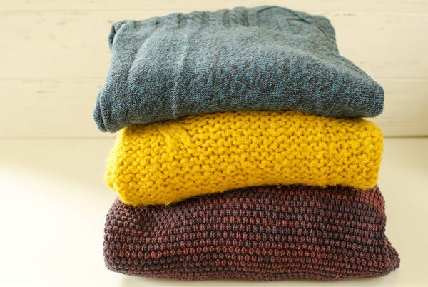  Stack of sweaters on white wooden background
