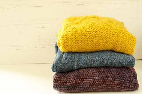 Stack of sweaters on white wooden background