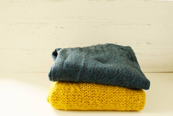 Stack of sweaters on white wooden background
