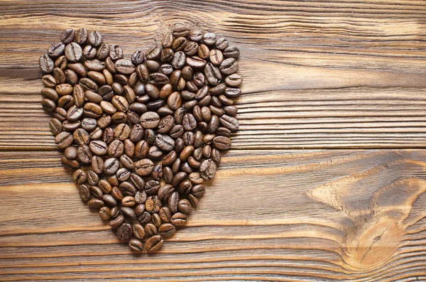 Heart from coffee beans on wooden background