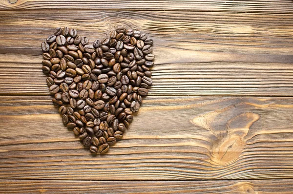 Heart from coffee beans on wooden background