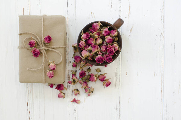 Кубок с сухими розами и подарочной коробкой на деревянном фоне
