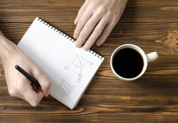 Mannen handen schrijven in Kladblok en kopje koffie op houten ta — Stockfoto