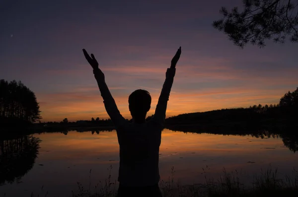 Hombre saludando puesta de sol de pie cerca del lago y — Foto de Stock