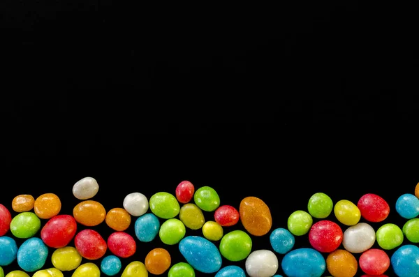 Bunte Bonbons auf schwarzem Hintergrund mit Platz für Text — Stockfoto