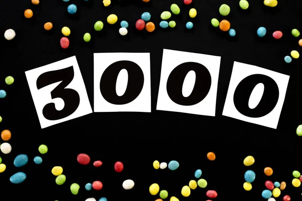 Numéro 3000 avec bonbons multicolores autour sur fond noir — Photo