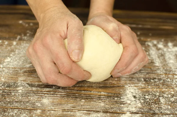 El ahşap arka plan üzerinde hamur yoğurmak