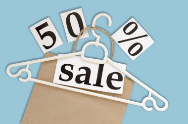 % 50 satış. Kraft kağıt torba ve askı mavi arka plan üzerinde