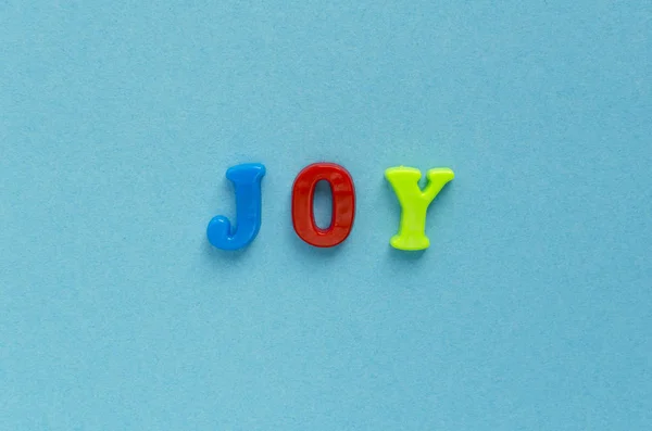 Word "joy" of plastic magnetic letters on blue background — Stock Photo, Image