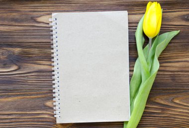 Not defteri ve Sarı laleler ahşap masa üzerinde. metin için yer