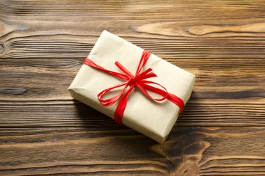 kraft kağıt ve kırmızı kurdele ahşap backgro üzerinde sarılı hediye kutusu