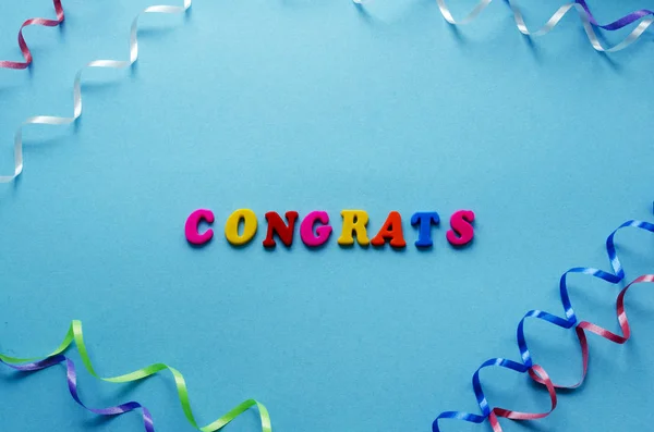 Слово "поздравления" из магнитных букв и серпантина на голубом папе — стоковое фото