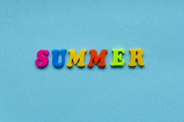 Parola "estate" di lettere magnetiche in plastica colorata su carta blu — Foto Stock