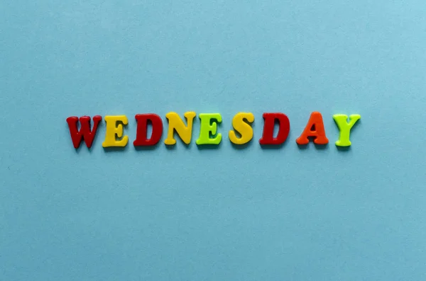 Ordet ”onsdag” av färgade plast magnetiska bokstäver på blå pap — Stockfoto