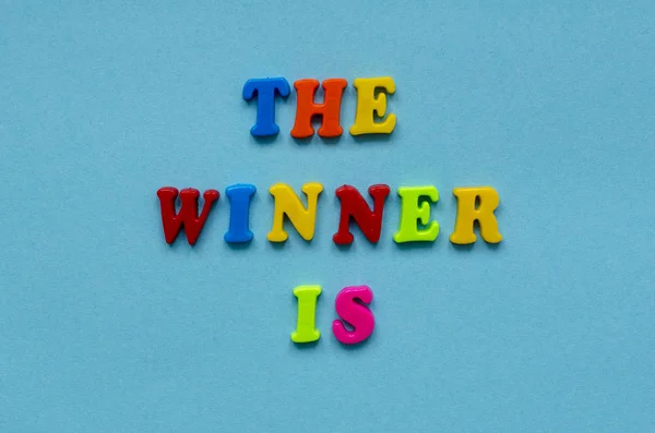 Frase "pemenangnya adalah" dari huruf magnetik plastik berwarna pada bl Stok Gambar Bebas Royalti