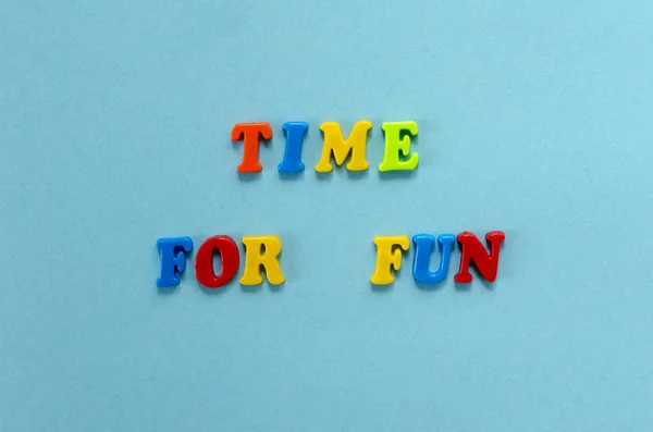 Frasa "waktu untuk bersenang-senang" dari huruf magnetik plastik berwarna pada blu Stok Foto
