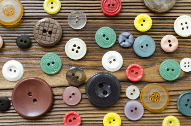 Colored plastic buttons on brown wooden background